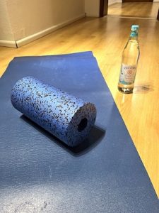 blaue Gymnastikmatte mit blauer black roll und wasserflasche daneben
